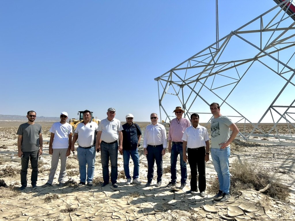 Project team beside a transmission tower under construction in the Turkmen desert